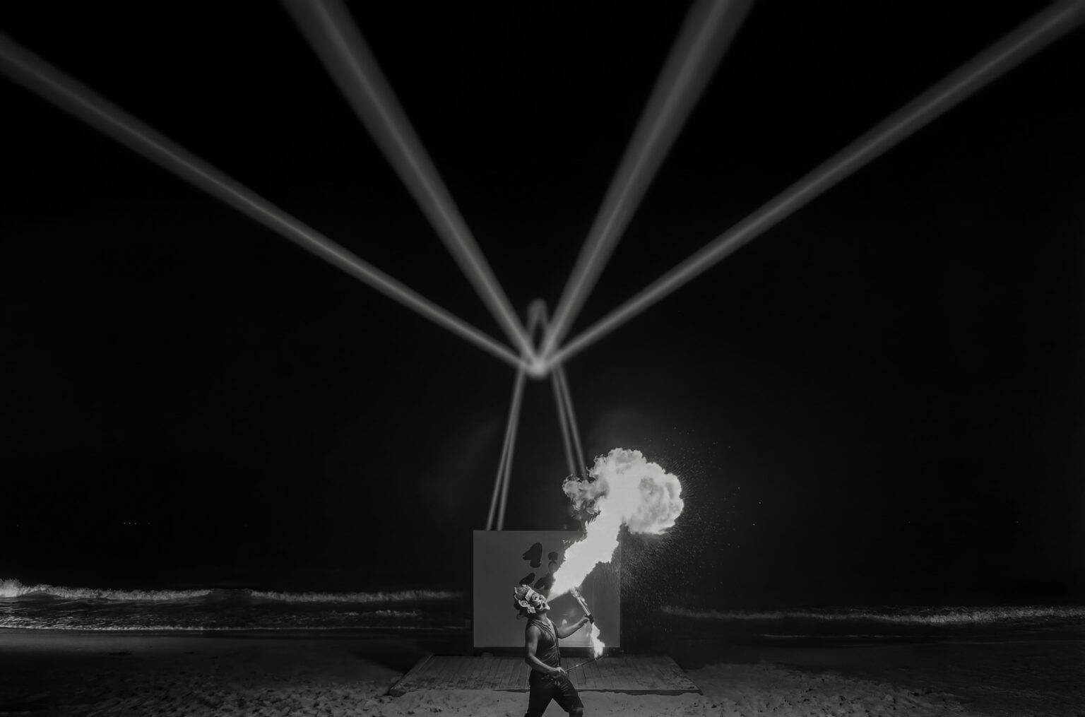 Night beach performance lit by beams of light